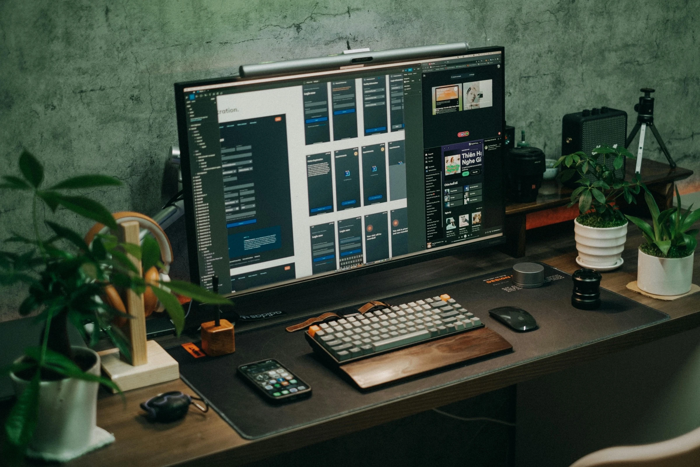 UI designer workspace with Figma open on a monitor showing mobile screen layouts